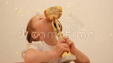 小女孩为胜利和奖赏而欢欣鼓舞，亲吻并拥抱冠军`冠军杯，获得冠军第一名